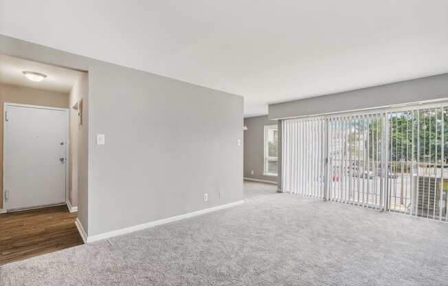 an empty living room with a sliding glass door to a balcony