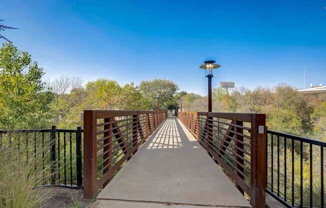 A bridge with a metal railing and a light post on top at Infinity on the Point Apartments, Dallas