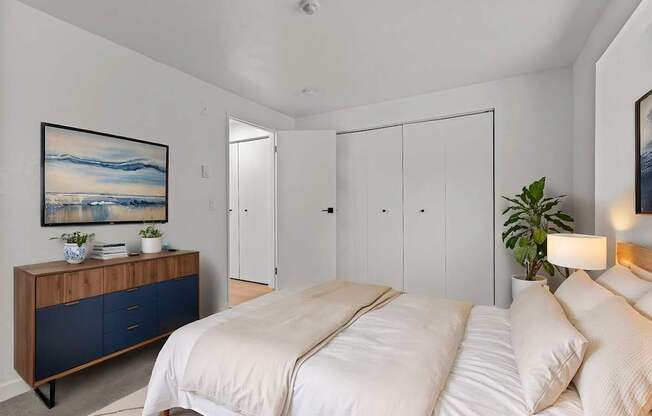 A bedroom with a large bed and a wooden cabinet with blue drawers.