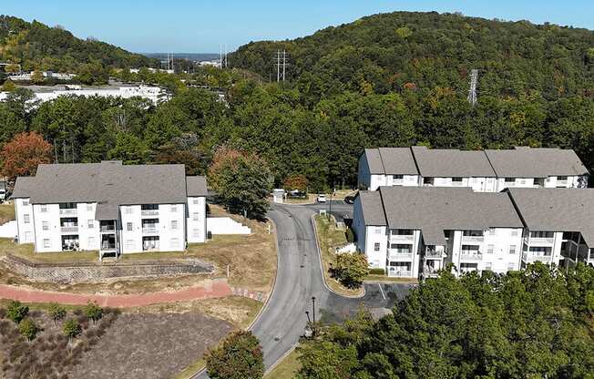 an aerial view of an apartment complex with a road and trees