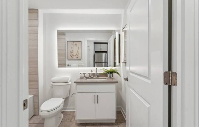 A white bathroom with a toilet, sink, and cabinet.
