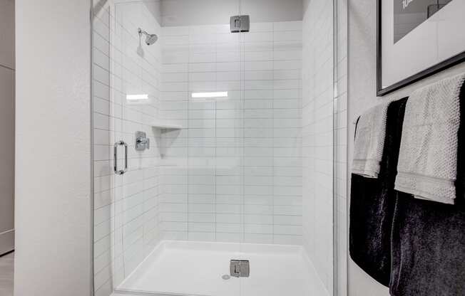 a white shower with white tiles in a bathroom