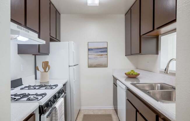 A kitchen with white and brown cabinets, a white stove, and a white refrigerator.