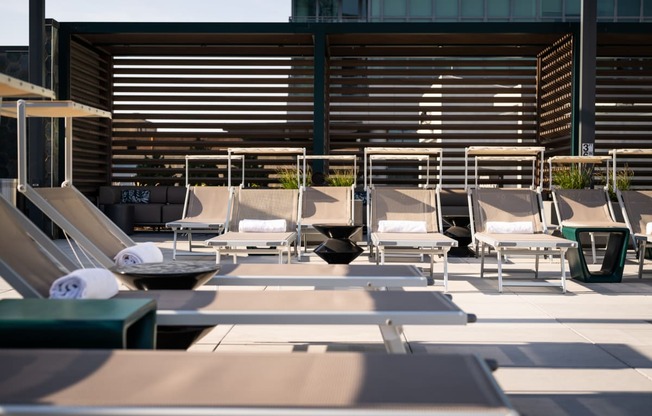 a row of lounge chairs on a patio with a building in the background