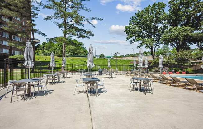 a patio with tables and umbrellas next to a pool