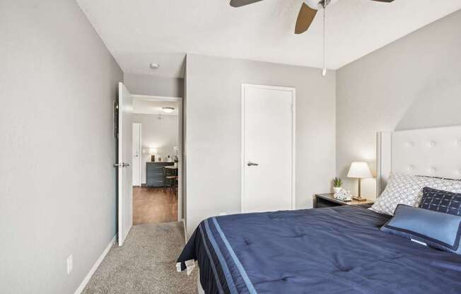 A bedroom with a bed, nightstand, and a ceiling fan.