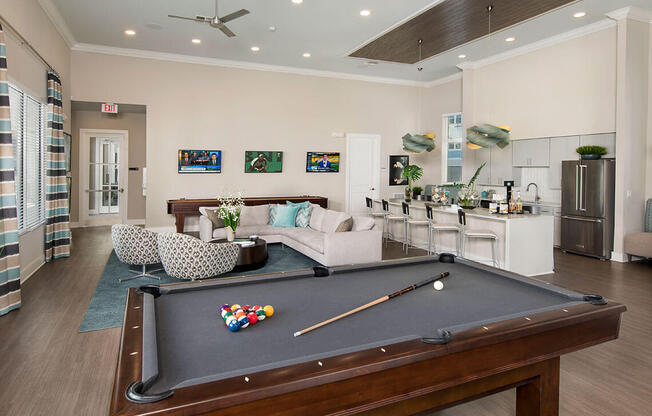 A pool table is in the middle of a room with a ceiling fan.