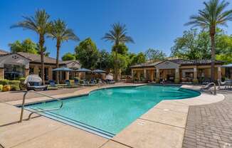A swimming pool surrounded by palm trees and lounge chairs.