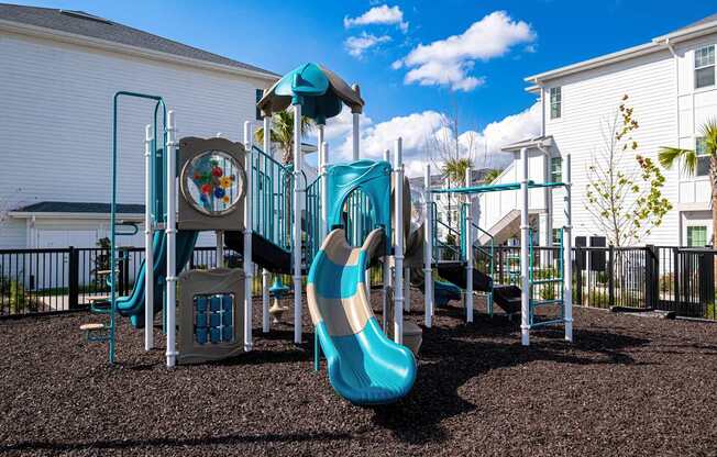 A playground with a blue slide and a brown ground.