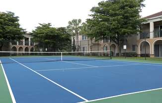 a blue tennis court in front of an apartment building