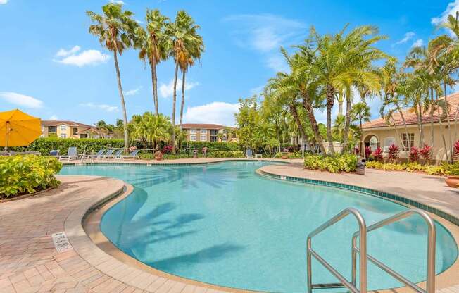 A swimming pool surrounded by palm trees and a yellow umbrella.