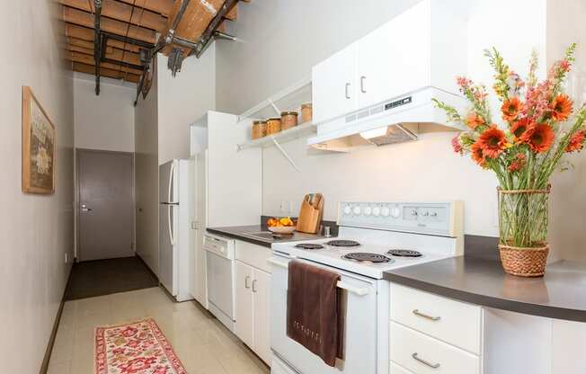 a kitchen with white appliances and a vase of flowers