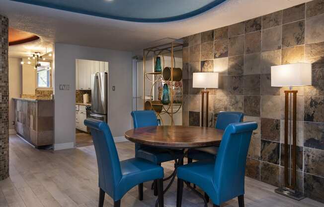 a dining area with a table and chairs and a kitchen in the background