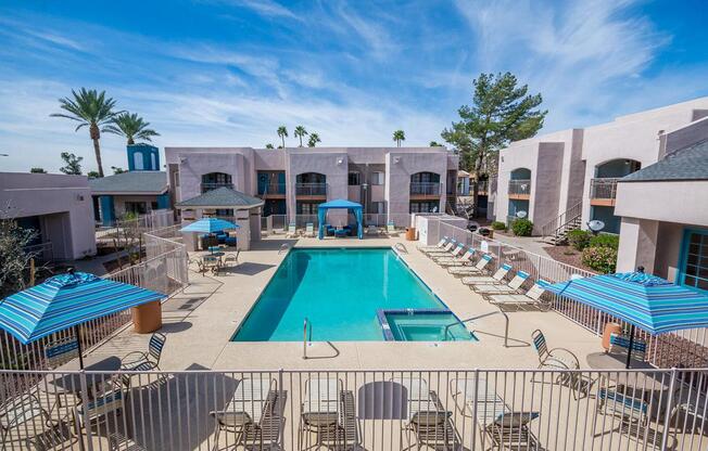 A large swimming pool surrounded by lounge chairs and umbrellas.