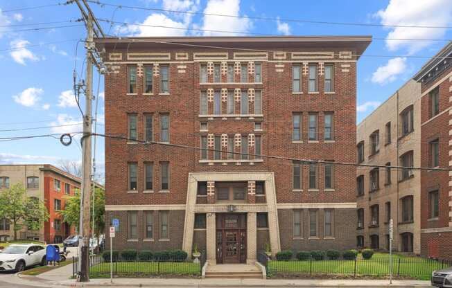 a red brick building with a large doorway and a black wrought iron fence in front of it