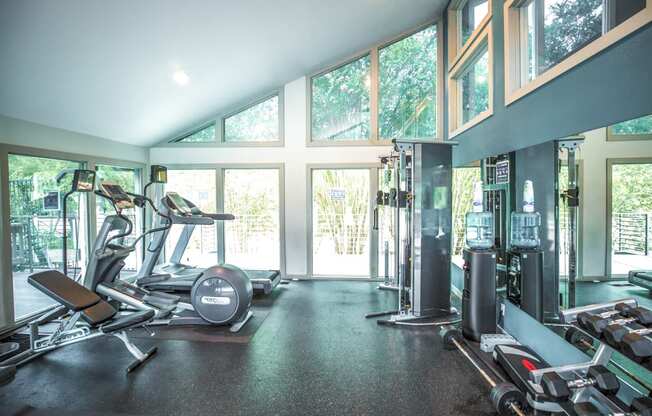 a gym with cardio equipment and windows with views of the trees