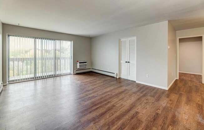 an empty living room with wood floors and a large window