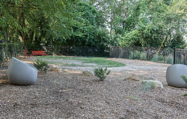 A garden with two large spherical objects and a red bench.