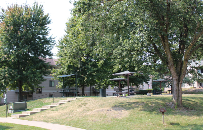 a grassy area with trees and buildings in the background