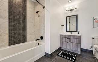 A bathroom with a white tub and a wooden vanity.