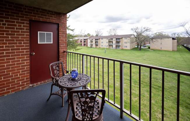 Balcony with two chairs and a table at Rockdale Gardens Apartments*, Baltimore, MD