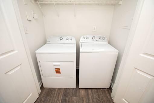 Two white front loading washing machines in a small laundry room.