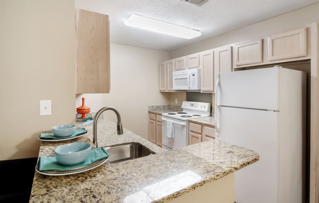a kitchen with white appliances and a granite counter top at Avalon Apartment Homes, Starkville, 39759