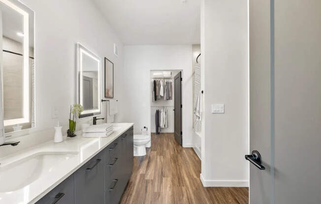 A bathroom with a white counter top and a wooden floor.