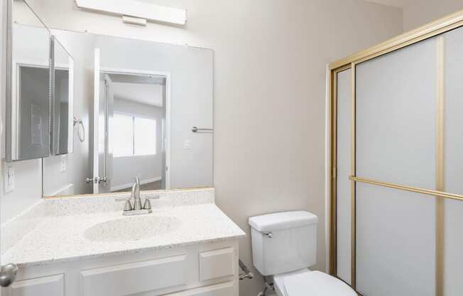 a bathroom with a toilet and a sink and a mirror at Huntington Terrace North Senior, Huntington Beach, CA