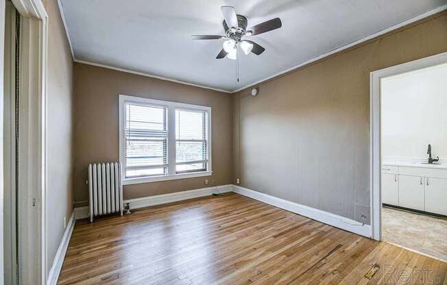 A room with a ceiling fan and wooden flooring.