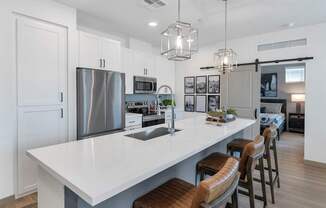 A modern kitchen with a large island and stools.
