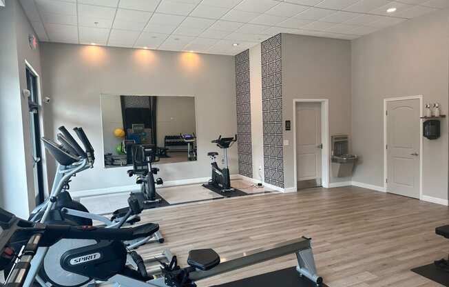 a gym with cardio machines and a mirror on the wall