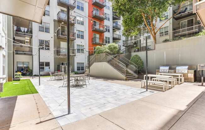 A patio area with a table and chairs is surrounded by apartment buildings.