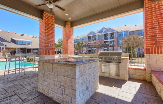 a large outdoor kitchen with a grill and a pool at Platinum Castle Hills, Lewisville, TX