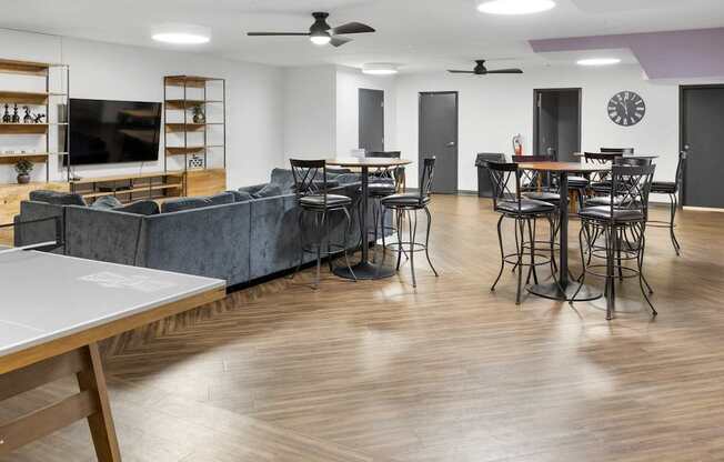 A spacious living room with a grey sofa and a ping pong table.