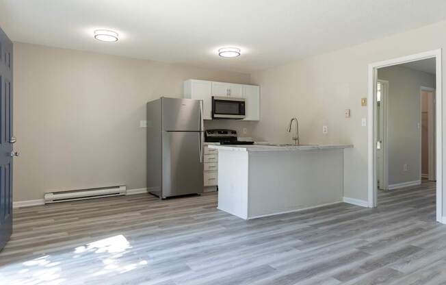A kitchen with a refrigerator, microwave, and stove top oven.