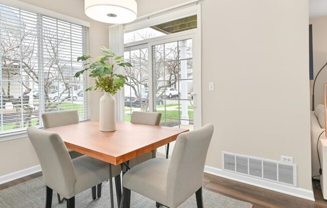 dining table with four chairs situated in a corner near the back sliding glass door of a Farmington Lakes home