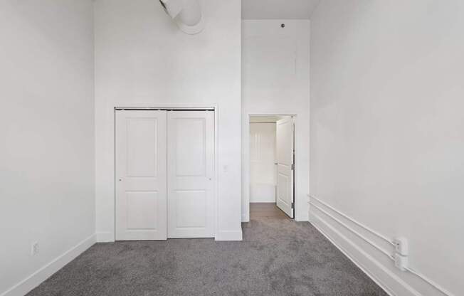 A bedroom with a grey carpet and white walls.