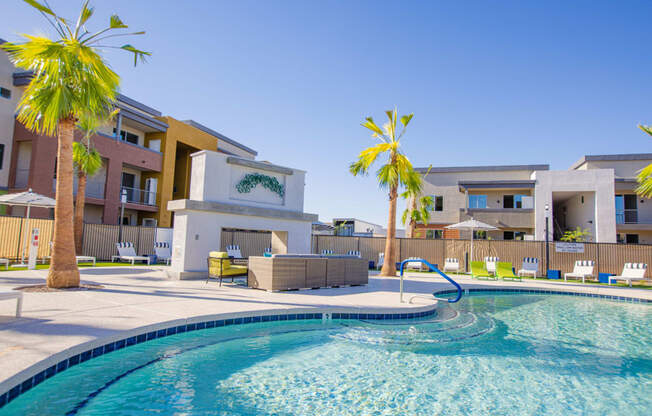 a swimming pool with palm trees and apartments in the background