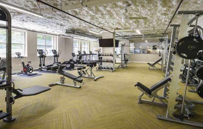 a gym with weights and cardio equipment in a building with exposed ceilings