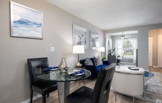 A modern dining room with a glass table and chairs.