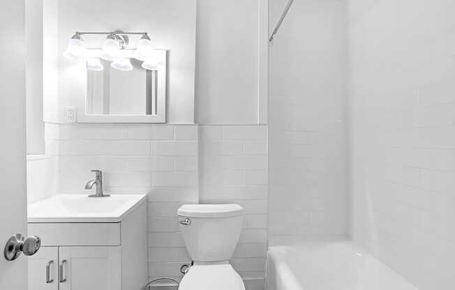 A white bathroom with a toilet, sink, and mirror.