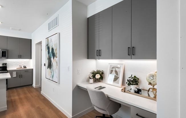 A modern home office with a desk, chair, and a framed artwork on the wall.