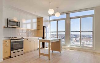 A kitchen with a microwave above the stove and a table in front of a window.