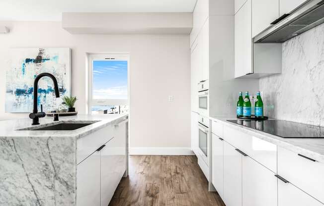 a kitchen with marble counter tops and white cabinets  at Oslo, Seattle, 98102