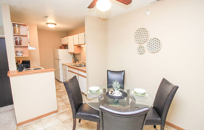 a dining room with a table and chairs and a kitchen in the background