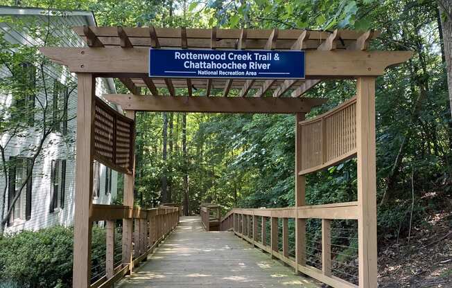 a walkway in a forest with a blue sign on the side of the walkway