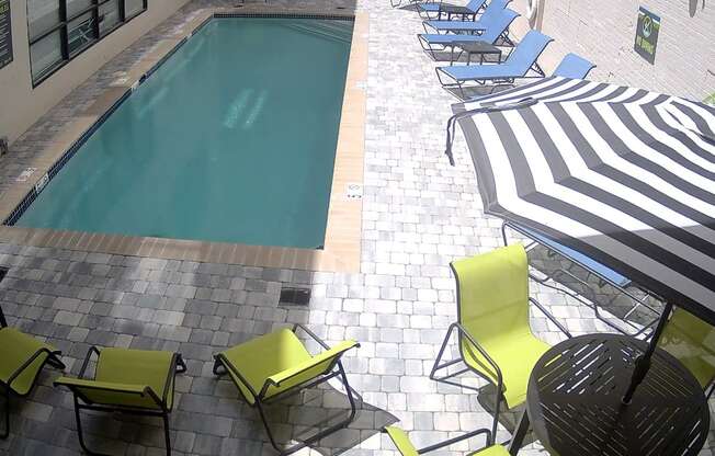 A pool surrounded by chairs and umbrellas.