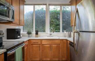 A kitchen with wooden cabinets and a stainless steel refrigerator.