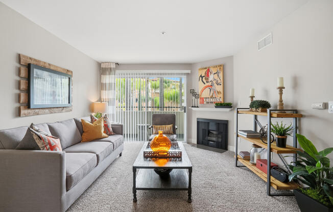 A living room with a grey couch, a coffee table, a fireplace, and a painting on the wall.